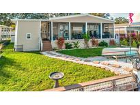 Single-wide manufactured home with covered porch, landscaped yard, and walkway at 8624 Fantasia Park Way, Riverview, FL 33578