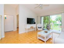 Bright living room with hardwood floors, white furniture, and sliding glass doors to balcony at 6059 Bahia Del Mar Blvd # 233, St Petersburg, FL 33715