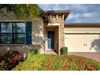 House exterior with stone accents, landscaping, and a two-car garage at 11976 Blazing Star Dr, Venice, FL 34293