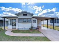 White single-wide manufactured home with carport and landscaped yard at 35216 Dodie Dr, Zephyrhills, FL 33541