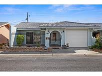 Light blue house with a white garage door, black gate, and landscaped yard at 10449 Larchmont N Pl, Pinellas Park, FL 33782