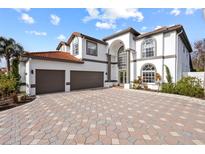 Elegant home featuring a three-car garage, beautiful stonework driveway, and a well-maintained lawn at 22847 Sonoma Ln, Lutz, FL 33549