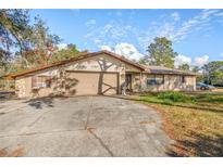 House exterior featuring a two-car garage and stone accents at 1130 Barranca Ave, Spring Hill, FL 34609