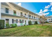 Two-story building with balconies, green accents, and manicured lawn at 200 Glennes Ln # 206, Dunedin, FL 34698
