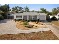 Updated home with gray brick exterior, landscaped yard, and a long driveway at 11556 70Th Ter, Seminole, FL 33772