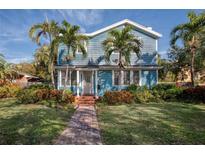 Charming blue house with brick pathway, lush landscaping, and palm trees at 165 21St Ne Ave, St Petersburg, FL 33704