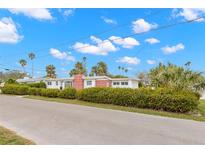 White and red brick mid-century modern home with a landscaped yard at 204 163Rd Ave, Redington Beach, FL 33708