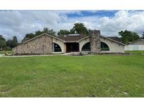 Stone exterior house with large windows and a spacious lawn at 5404 Glover Dr, Weeki Wachee, FL 34607