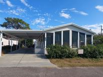 Single-wide manufactured home with carport and landscaped yard at 1760 Dorothy Blvd, Lutz, FL 33558