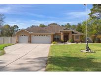 Tan house with three-car garage, lush lawn, and American flag at 5171 Bone Ln, Brooksville, FL 34604