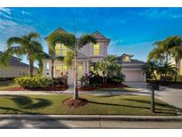 Beautiful two-story home with a pink exterior and lush landscaping at 620 Mirabay Blvd, Apollo Beach, FL 33572