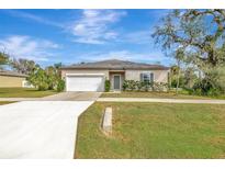 Tan house with white garage door and landscaping at 807 Garden Oaks Sq, Seffner, FL 33584