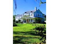 Two-story home with wrap-around porch and large green lawn at 13621 Mcintosh Rd, Thonotosassa, FL 33592