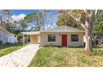 Tan house with red door, driveway, and landscaping at 15572 George Blvd, Clearwater, FL 33760