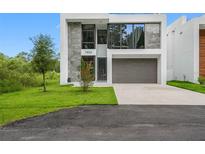 Stylish modern home showcasing front yard, stone facade, and two-car garage at 7602 Antilla St, Tampa, FL 33625