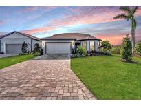 Single story home with a two-car garage and manicured lawn at sunset at 8705 Coastal Key Way, Parrish, FL 34219
