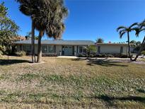 House exterior featuring a light-colored facade, teal door, and palm trees at 1401 Gulf Blvd, Belleair Beach, FL 33786