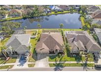 A captivating aerial view of a home backing onto a serene lake, surrounded by lush greenery and neighboring properties at 1406 Deerbourne Dr, Wesley Chapel, FL 33543