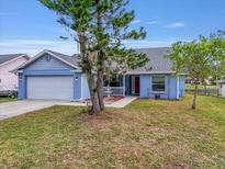 Charming light blue house with a two-car garage and well-manicured lawn at 5506 79Th E Ave, Palmetto, FL 34221