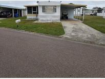 White single-wide mobile home with carport and small yard at 119 Saint Pierres Way, Apollo Beach, FL 33572