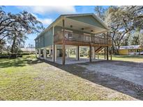 Elevated home with green siding, deck, and covered parking at 39744 Amber Ave, Zephyrhills, FL 33540