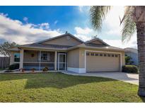 Tan house with screened porch, two-car garage, and landscaped lawn at 4613 72Nd E Ct, Bradenton, FL 34203