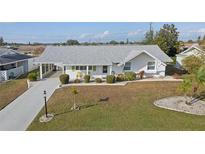 White single-story home with grey roof, landscaping, and driveway at 719 Indian Wells Ave, Sun City Center, FL 33573