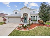Charming two-story home with a well-manicured lawn, arched entrance, and attached two-car garage at 4104 Warwick Hills Dr, Wesley Chapel, FL 33543