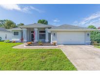 Single-story home with gray exterior, two-car garage, and well-maintained landscaping at 10328 Henderson St, Spring Hill, FL 34608