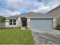 One-story house with gray siding, stone accents, and a two-car garage at 36141 Welsh Glade Rd, Dade City, FL 33525