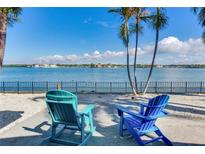 Relaxing waterfront view with two chairs, palm trees, and peaceful water at 16101 6Th E St, Redington Beach, FL 33708