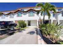 Inviting townhouse with a neutral color palette, lush landscaping, and driveway leading to a private one car garage at 273 Madeira Cir, Tierra Verde, FL 33715
