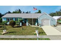 Cute light blue house with a white garage door, and nicely landscaped lawn at 2575 Shenandoah St, North Port, FL 34287
