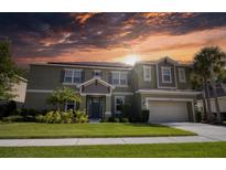 Two-story house with a green exterior, three-car garage, and landscaping at 26888 Fiddlewood Loop, Wesley Chapel, FL 33544