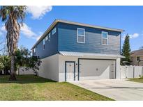 Two-story home with a blue exterior, white garage, and a landscaped yard at 3276 Sea Grape Dr, Hernando Beach, FL 34607