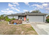Gray house with solar panels, orange door, and landscaped yard at 5956 Nyberg Rd, North Port, FL 34291