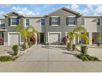 Two-story townhome with gray siding, two-car garage, and palm trees at 2920 Evergreen Elm Pass, Wesley Chapel, FL 33543
