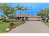 Charming single-story home featuring mature landscaping, a brick driveway, and an attached two-car garage at 1000 Chillum Ct, Safety Harbor, FL 34695