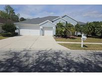 Two-story house with light blue exterior, two-car garage, and palm trees at 5125 Silver Charm Ter, Wesley Chapel, FL 33544