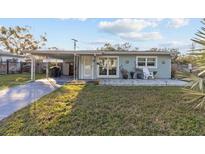 Light blue house with a covered patio and well-maintained lawn at 1890 San Mateo Dr, Dunedin, FL 34698