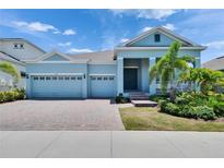 Charming one-story home featuring a three-car garage, brick driveway and tropical landscaping at 1074 Signet Dr, Apollo Beach, FL 33572