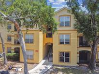 Condo building with balconies, yellow walls, and mature trees in a residential community at 5606 Pinnacle Heights Cir # 304, Tampa, FL 33624