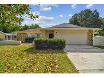 One-story house with stone accents and a two-car garage, nestled on a lawn with autumn leaves at 22368 Southshore Dr, Land O Lakes, FL 34639