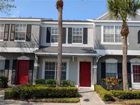Charming townhome with vibrant red door, lush landscaping and tropical palm trees, offers inviting curb appeal at 262 Countryside Key Blvd, Oldsmar, FL 34677