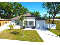 Charming single-story home with white exterior, manicured lawn, and attached garage at 408 E Hanlon St, Tampa, FL 33604