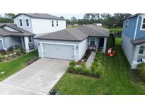 Single-story home with gray garage door, landscaped yard, and walkway at 3329 Fresno Pl, Zephyrhills, FL 33541