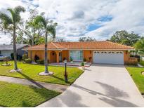 Orange house with a large yard, palm trees, and a long driveway at 6888 121St N St, Seminole, FL 33772