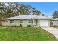 Charming single-story home features a light-green exterior, gray metal roof, well-manicured lawn, and attached one-car garage at 807 Leffingwell Ave, Ellenton, FL 34222