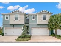 Inviting townhome featuring a two-car garage, manicured landscaping, and a welcoming entrance at 1003 Starboard Ct, Oldsmar, FL 34677