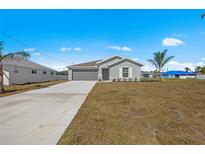 Single-story home with gray siding, attached garage, and a grassy front yard at 23396 Steeple Ave, Port Charlotte, FL 33980